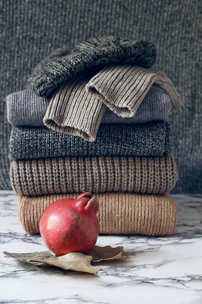 A close-up of a neatly folded pile of neutral-colored sweaters and a stack of well-organized jeans in a closet. The lighting is soft, highlighting the texture of the fabrics. This image emphasizes the concept of simplicity and organization within a capsule wardrobe.