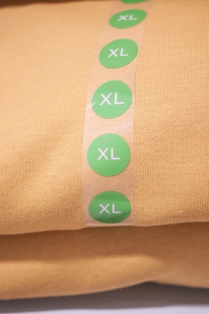 A close-up of a brand-specific size chart on a clothing tag, highlighting the various measurements and sizes provided. The image should emphasize the importance of paying close attention to these details.