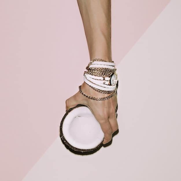A close-up shot of a woman's hands, showcasing chunky gold bracelets and rings, paired with a sleek little black dress sleeve visible in the background, highlighting the contrast between the classic dress and modern, bold jewelry.