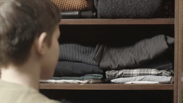 Close-up of a well-organized closet with essential men's clothing items: a white t-shirt, dark wash jeans, a navy blazer, and khaki chinos. Each item is neatly folded or hung, emphasizing the importance of a versatile and foundational wardrobe.