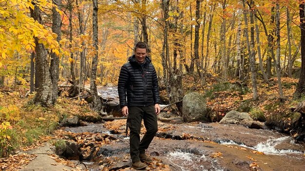 A man hiking in a forest, wearing a field jacket with cargo pants and hiking boots. The image should emphasize the jacket's practicality and durability in an outdoor setting.