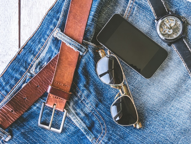 A close-up shot of various men's accessories, including a stylish watch, leather belt, sunglasses, and a patterned scarf. The focus is on the details and how these accessories can enhance an overall look.