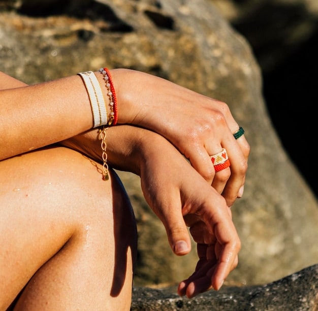 A close-up shot of a woman's hands adorning stacked rings and bracelets with natural stones, paired with a delicate, floral-printed tunic. The image highlights the intricate detail and earthy tones of boho accessories.