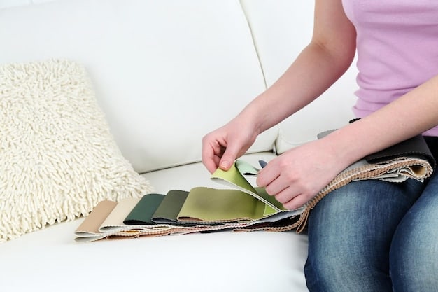 A close-up of a woman's hand showcasing various fabric swatches in different shades of beige, cream, and tan, arranged against a wooden table. The textures of the fabrics range from smooth silk to chunky knit, emphasizing the subtle variations within a monochromatic color scheme. Natural light streams in, highlighting the tactile quality of the materials.