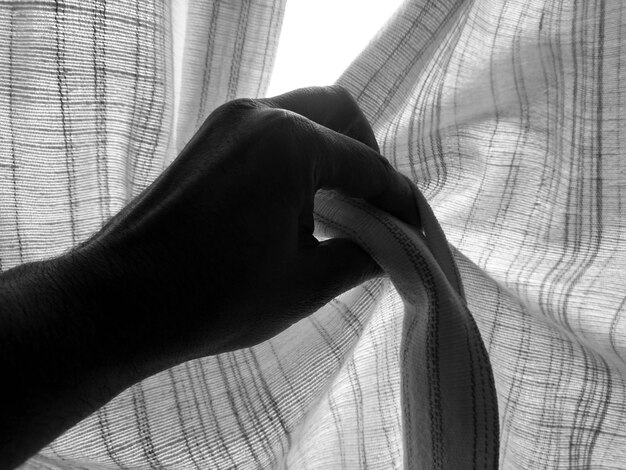 Close-up shot of two fabrics being held together. One fabric has a thin black and white stripe pattern and the other has a vibrant red and pink floral pattern. The textures of the fabrics are clearly visible, showing the details of each print.