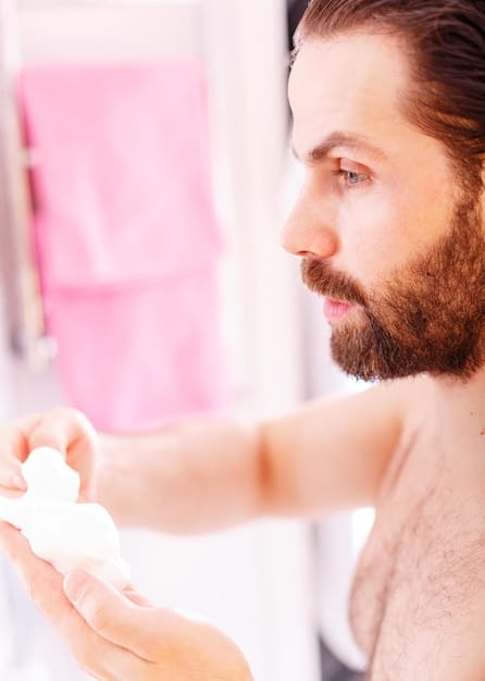 A close-up shot of a Canadian man's hands lathering a creamy, foaming face wash. His skin is clear and healthy-looking. The background is a modern bathroom with natural light.
